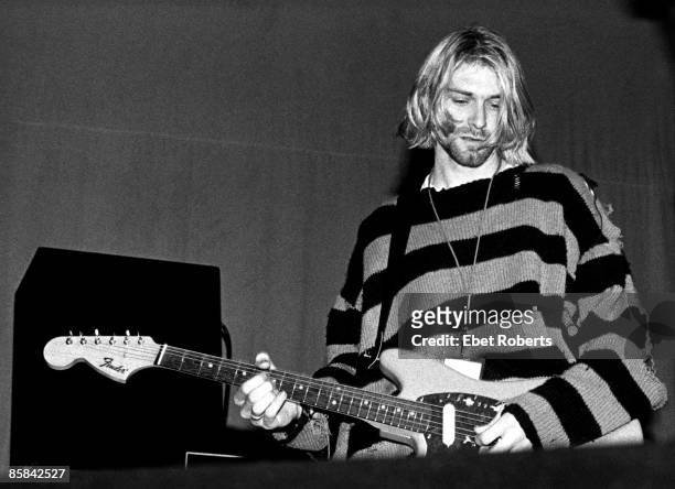 Kurt Cobain tocando en el New Music Seminar vistiendo una polera grunge a rayas.